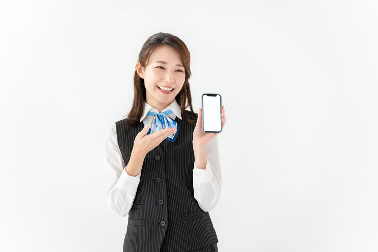 笑顔で片手にスマートフォンを持つ制服姿の女性